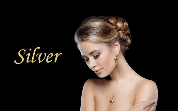 Model wearing a handcrafted silver-toned statement necklace and matching earrings with red gemstone accents, featuring the text 