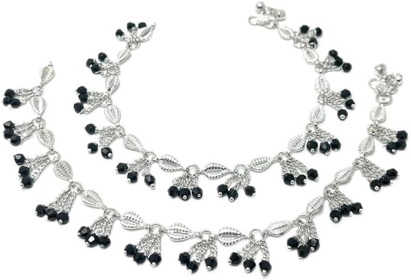 Model wearing silver-plated leaf-link anklets with black bead clusters and soft bell accents.
