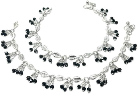 Model wearing silver-plated leaf-link anklets with black bead clusters and soft bell accents.
