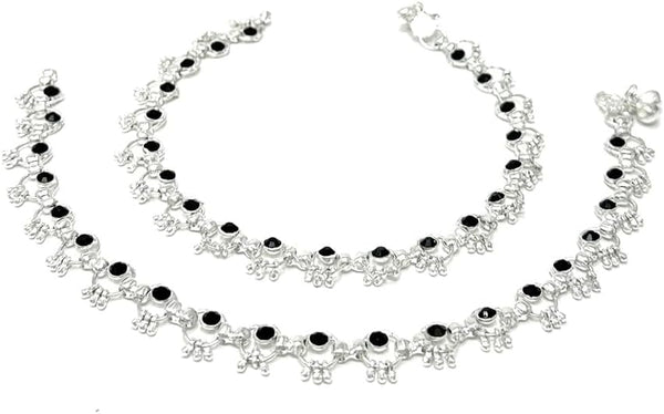 Model wearing silver-plated ring-link anklets with round black stone accents and soft bell chimes.
