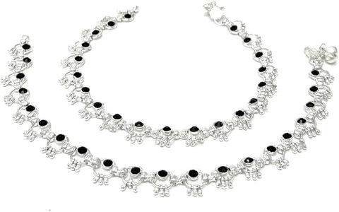 Model wearing silver-plated ring-link anklets with round black stone accents and soft bell chimes.
