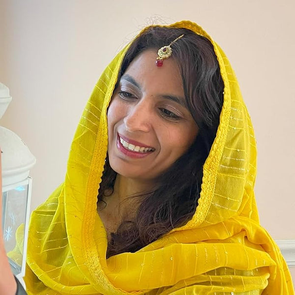 Close-up of the fish hook attachment on a gold-tone Kundan maang tikka for secure hair styling.
