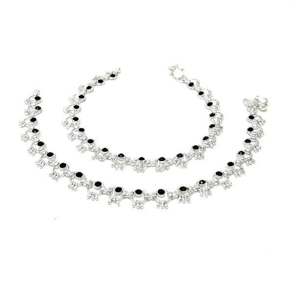 Model wearing silver-plated ring-link anklets with round black stone accents and soft bell chimes.
