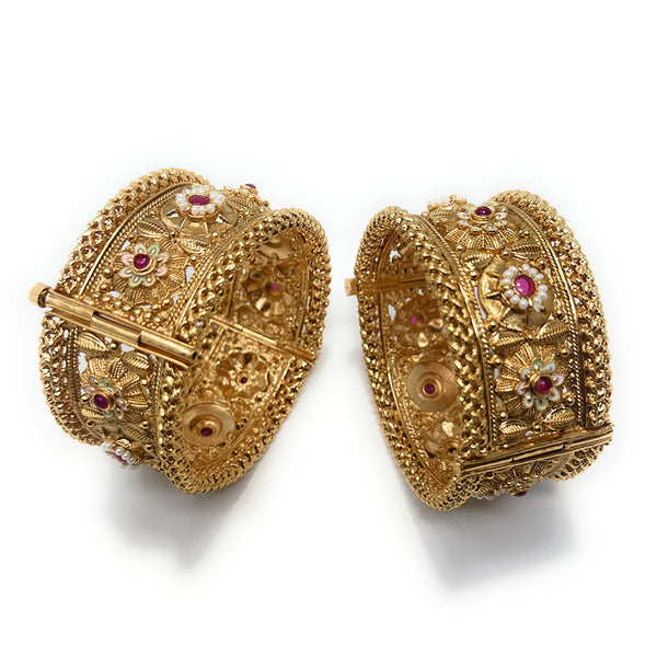 Model in red outfit wearing gold-plated Meenakari floral kada bangles with red Polki stones and pearl accents.