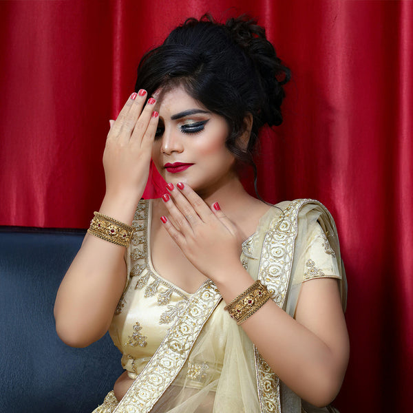 Street style fashion featuring matching gold-tone kada bangles with a vibrant Meenakari enamel floral pattern.
