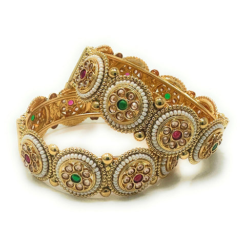  Studio model wearing gold-tone filigree kada bangle pair with red and green stones.

