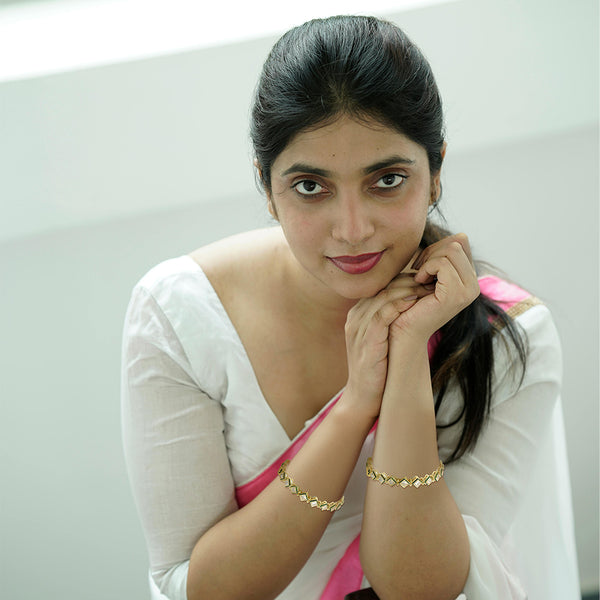 Studio portrait of a model wearing a matching openable Kundan bangle set with square stones.
