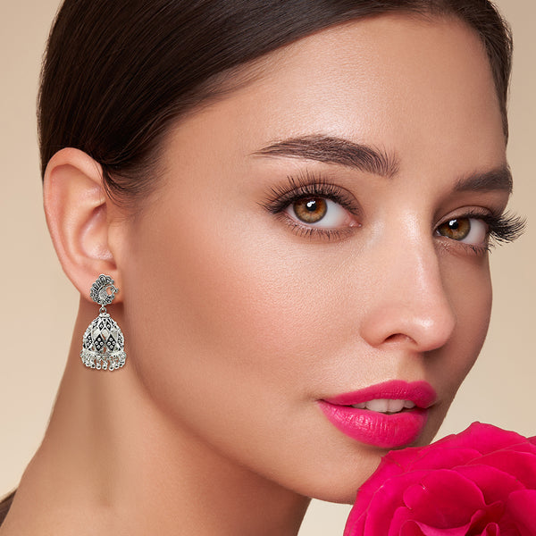 Close-up of peacock-inspired stud and lattice silverwork detail on handmade jhumka earrings

