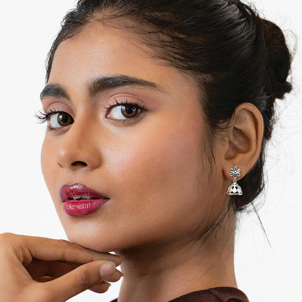 Close-up of open-petal floral stud and faceted silver jhumka drop showing intricate cutwork detail
